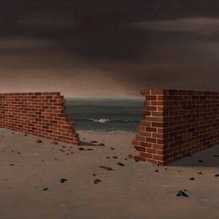 A broken wall on a beach offers a view through to the sea under a dark sky