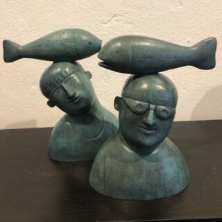 A man with a fish on his head and woman with fish on her head