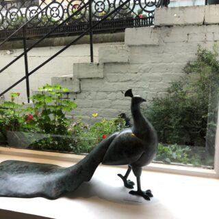 sculpture of a peacock on a window ledge