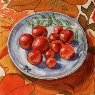 A patterned plate of tomatoes on a brightly coloured tablecloth
