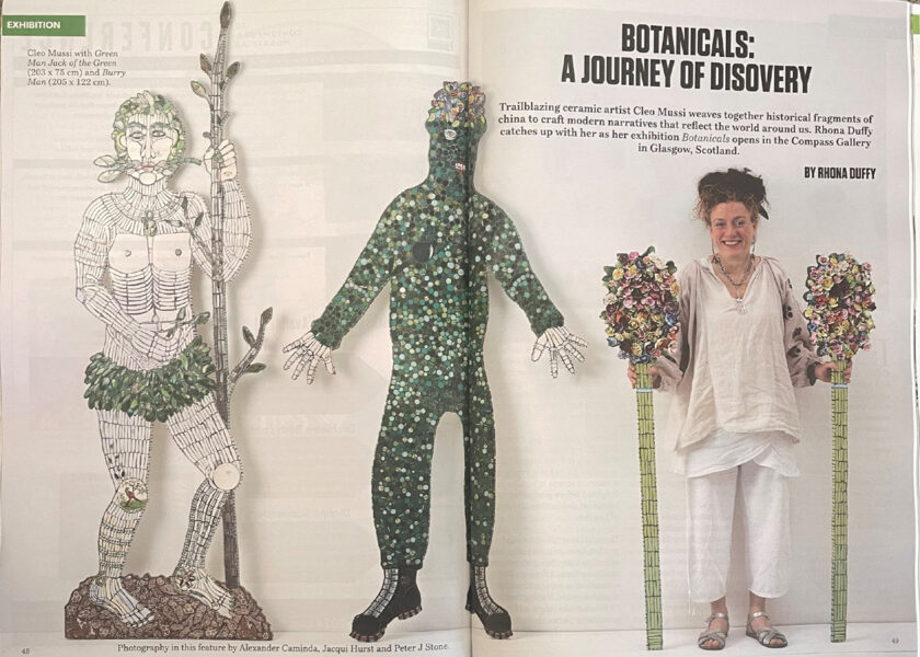 artist stood with green man and the burry man holding flower staffs 